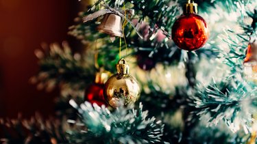 Nahaufnahme eines beschmückten Weihnachtsbaums, auf dem unter anderem eine goldene und eine rote Kugel hängen.