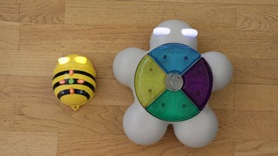Der Bee-Bot steht neben dem Glow and Go Bot auf Holzboden.