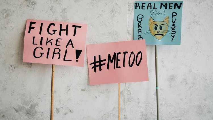Mehrere Schilder auf Stangen mit politischen, feministischen Botschaften. Unter anderem: "Fight like a girl", "#Metoo", etc.