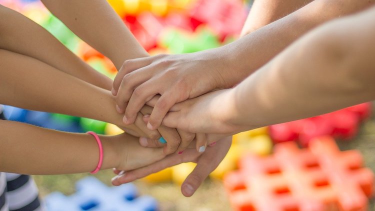 Nahaufnahme von mehreren Kinderhänden, die aufeinander liegen.