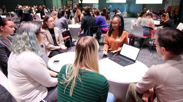 Ein Bild von der Safer Internet Day Fachtagung 2024: Eine Jugendliche sitzt mit mehreren Erwachsenen an einem Tisch und erklärt etwas. 