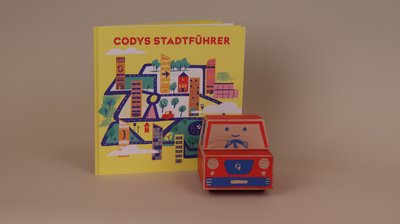 Lernroboter Cody vor der Anleitung "Codys Stadtführer"
