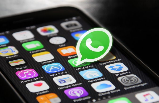 Der Bildschirm eines Smartphones, aus dem das Logo von "WhatsApp" herausragt