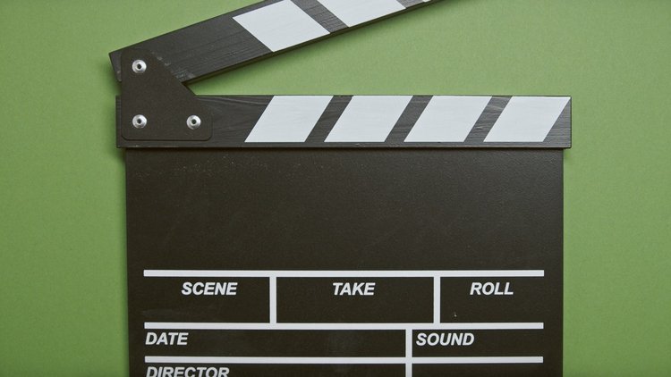 Nahaufnahme einer Filmklappe vor grünem Hintergrund