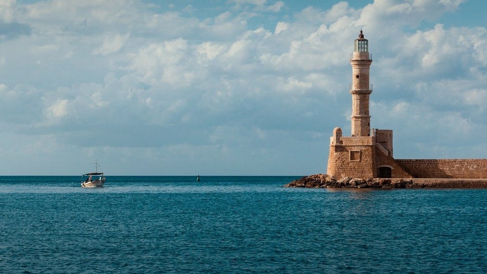 Ein Foto zeigt das Meer, blau-strahlenden Himmel und einen Leuchtturm.