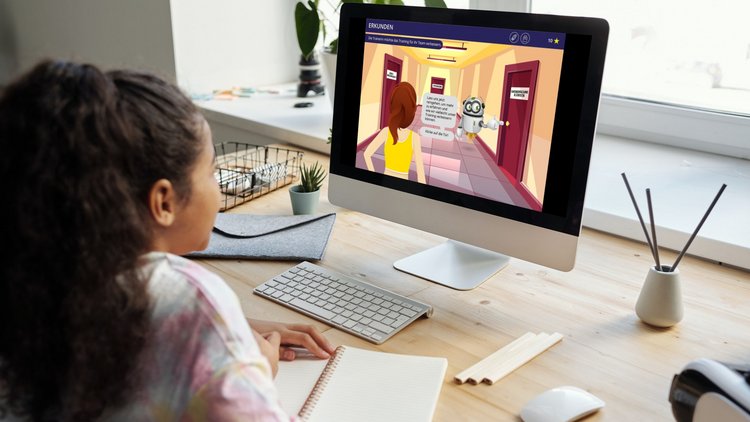 Ein Mädchen sitzt an einem Computer und spielt Robitopia. 