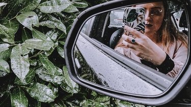 Eine Frau ist im Autospiegel zu sehen, als sie sich selbst fotografiert