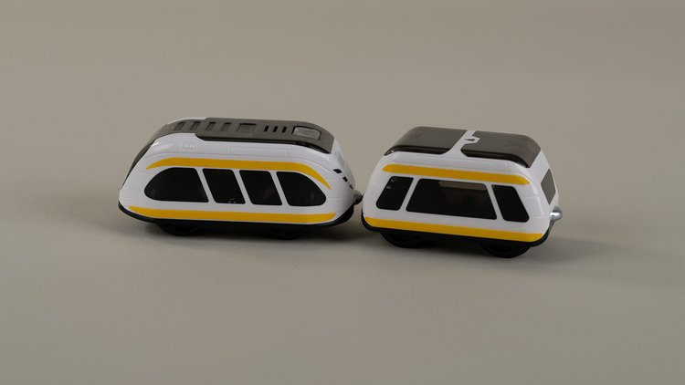 Smart Train vor hellgrauem Hintergrund. Der Smart Train besteht aus einer weißen Lok mit schwarzen Fenstern und gelben Streifen und einem ebensolchen Waggon.