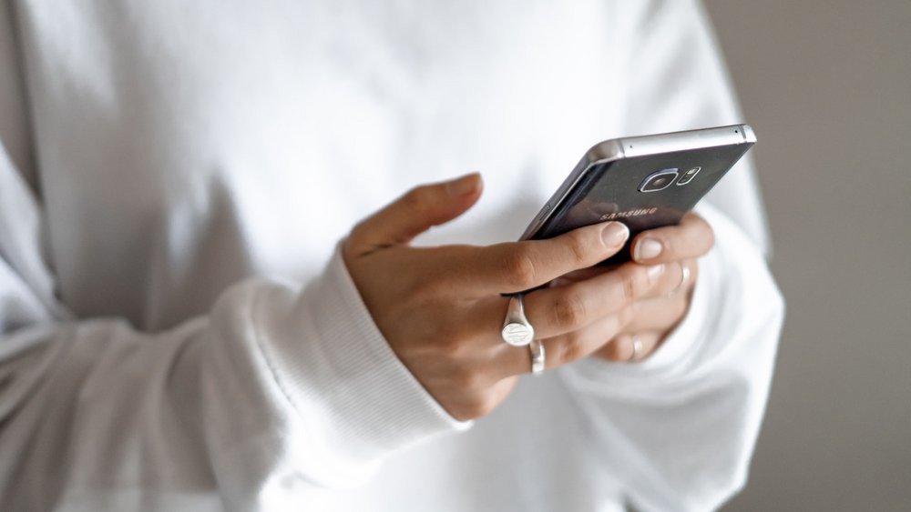 Chatten Texting Smartphone tippen Nahaufnahme von zwei Händen, die ein Smartphone halten und darauf tippen.
