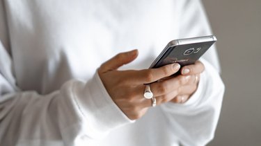 Nahaufnahme von zwei Händen, die ein Smartphone halten und darauf tippen.