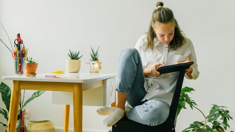 Ein junges Mädchen sitzt mit einem Tablet an einem Tisch