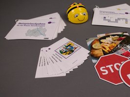 Ein Bee-Bot steht umgeben von diversen Lern-Materialien und Kärtchen.