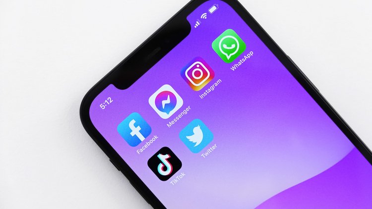 Nahaufnahme eines Smartphones, am Display sind die App-Symbole diverser Social Media-Apps zu sehen.