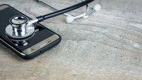 Ein Stethoskop liegt auf einem Smartphone