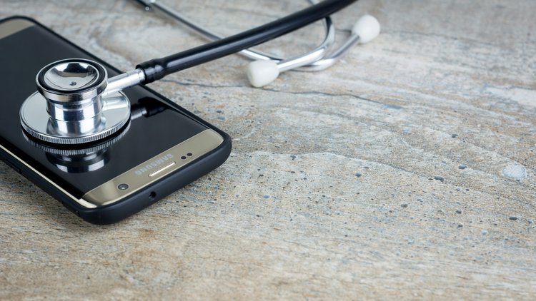Ein Stethoskop liegt auf einem Smartphone
