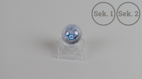 Ein Foto des Sphero Mini Roboters auf transparenter Halterung. Rechts oben steht "Sek. 1" und "Sek. 2".