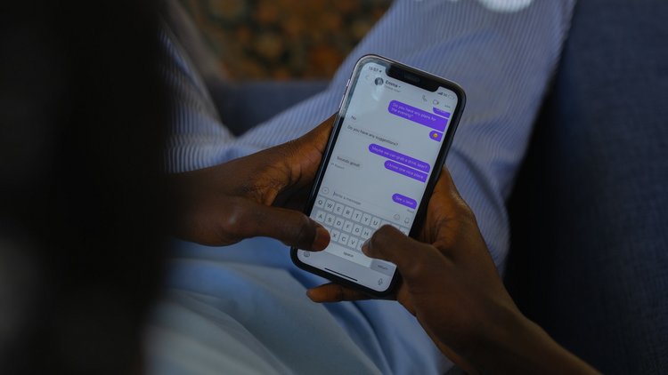 Foto über die Schulter einer Person, die ein Smartphone hält. Am Display ist ein Chat geöffnet.