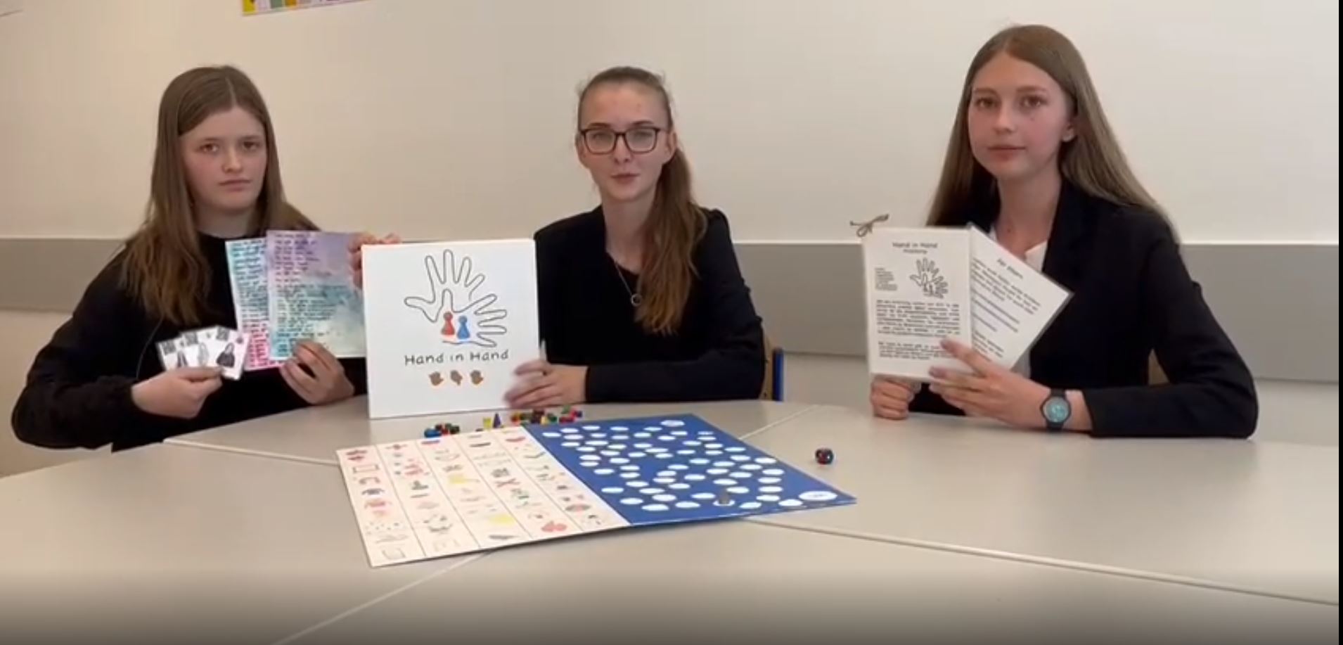 Drei Schülerinnen präsentieren das inklusive Brettspiel "Hand in Hand" zum Erlernen der Gebärdensprache
