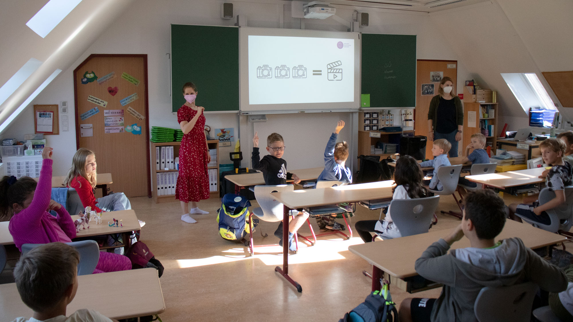 Zwei Pädagoginnen des Wiener Bildungsservers stehen vor einer Schulklasse und sprechen.
